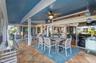 Covered patio featuring stone-finish flooring, a painted tray ceiling, a dual-blade ceiling fan, and large-format sliding glass doors