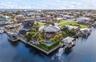 Waterfront property featuring a private boat lift, a custom-shaped swimming pool, extensive wrap-around decking, and a seawall perimeter