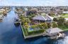 Waterfront property featuring a private boat lift, a custom in-ground swimming pool, an elevated wooden deck, and mature palm landscaping on a corner 