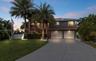 Two-story residence featuring a metal roof, attached two-car garage, elevated wooden staircase, wrap-around balcony with wooden railings, and mature p