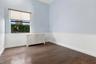 Interior room featuring wood-finish flooring, white beadboard wainscoting, and a single-pane window with a light-filtering roller shade