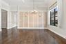 Interior space featuring wood-finish flooring, tray ceiling with crown molding, paneled accent wall, and multi-arm chandelier