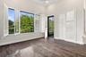 Wood-finish flooring, white plantation shutters, vaulted ceilings, and a framed glass door with screen panel