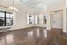 Tray ceiling, wood-finish flooring, multi-pane windows with black frames, and multi-arm chandelier