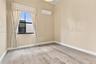Room featuring wood-finish flooring, a wall-mounted ductless air conditioning unit, and a window with a dark metal frame