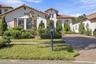 Stucco exterior with a clay tile roof, arched entryway, and paver driveway