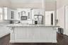 Kitchen featuring white cabinetry with crown molding, stone countertops, a large center island with corbel detailing, stainless steel appliances, and 