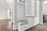 Built-in mudroom cabinetry featuring white shaker-style doors, beadboard backing, a pull-out storage drawer, and stone-surface countertop