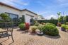 Spacious brick-paver patio featuring a herringbone pattern, exterior stucco finish, and manicured shrubbery