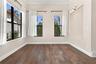 Room featuring dark wood-finish flooring, high ceilings with crown molding, black-framed windows, and a built-in recessed display niche with integrate