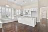 Kitchen featuring white cabinetry with glass-front uppers, a central island with stone-finish countertops, recessed lighting, plantation shutters, and