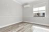 Neutral-toned room featuring wood-finish flooring, chair rail molding, crown molding, and a wall-mounted ductless air conditioning unit, completed by 