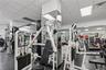 Fitness center featuring grid ceiling tiles, wall-to-wall mirrors, and durable rubber flooring