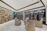 Floor-to-ceiling dry-stack stone accent wall, expansive built-in dark wood shelving, recessed lighting, and large-format tile flooring