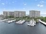 High-rise residential complex featuring a deep-water marina, private boat slips, extensive waterfront hardscaping, and lush tropical landscaping