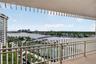 Covered balcony featuring vertical privacy screening and metal railing, overlooking a marina and waterfront landscape