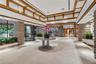Spacious interior featuring a coffered ceiling with wood trim, decorative brick pillars, tile flooring, and recessed lighting