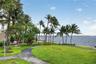 Waterfront grounds featuring mature palm trees, manicured lawns, and paved pathways