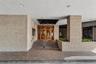 Building Exterior entrance featuring light-toned brick masonry, stone steps, dual wood-framed circular glass doors, recessed ceiling lighting, and int
