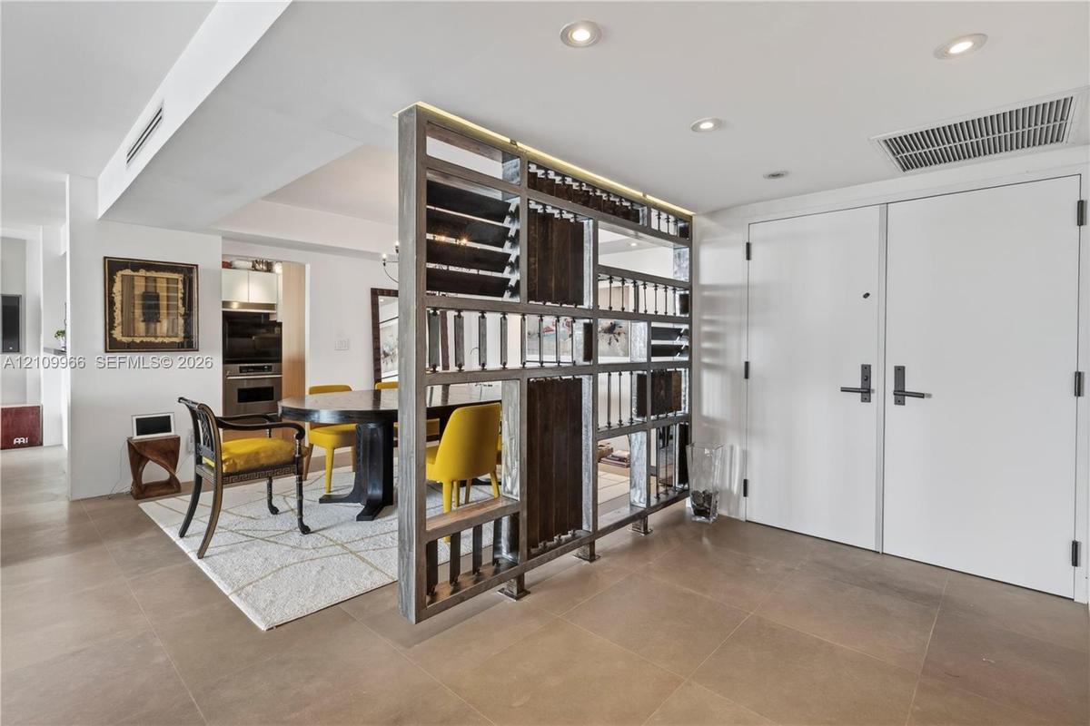 Custom wood-framed decorative partition, large-format tile flooring, recessed ceiling lighting, and double-entry doors
