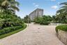 Paved pedestrian walkway featuring stone retaining walls, manicured landscaping, and mature palm trees