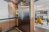 Kitchen featuring wood-veneer flat-panel cabinetry, professional-grade stainless steel refrigerator, black stone-composite countertops, and exposed co