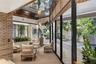 Interior space featuring a mirrored ceiling, exposed brick wall, floor-to-ceiling glass wall panels, and an outdoor water feature