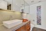 Wall-mounted wood-finish vanity with a rectangular vessel sink, solid-surface countertop, full-width mirrored cabinetry, and wall-mounted faucet