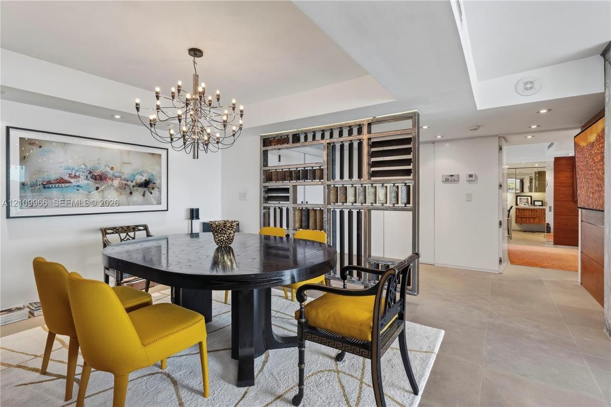 Open-concept dining area featuring a tiered metal and wood room divider, recessed ceiling lighting, a multi-arm chandelier, and stone-finish flooring