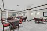 Large common area featuring neutral tile flooring, recessed lighting, crown molding with dark wood trim, structural support columns, and wall-mounted 
