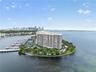 Waterfront high-rise building situated on a peninsula, featuring a private marina with boat slips, multiple hard-court tennis facilities, lush mature 