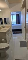 Bathroom featuring a dual-sink vanity with light-toned countertop, large wall-mounted mirror, and polished tile flooring