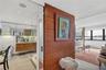 Floating wood-finish vanity with countertop, wood-panel accent wall with sliding door, recessed ceiling lighting, and large windows