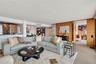 Open-concept living space featuring wood-paneled walls, large-format tile flooring, a concrete structural pillar, and built-in shelving