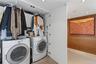 Laundry area featuring white front-load washer and dryer, built-in white cabinetry, wood-panel wall accents, and tile flooring