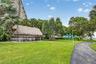 Landscaped grounds featuring a thatched-roof pavilion, paved walking paths, mature palm trees, and a play structure