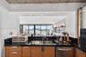 Kitchen featuring wood cabinetry, black solid-surface countertops, dual-basin stainless steel sink with a high-arch faucet, stainless steel dishwasher