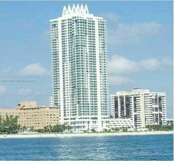 High-rise tower featuring a crown architectural detail, glass-enclosed balconies, and direct coastal proximity