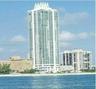 High-rise tower featuring a crown architectural detail, glass-enclosed balconies, and direct coastal proximity