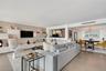Open-concept interior featuring large-format tile flooring, built-in high-gloss cabinetry, recessed accent lighting, and a multi-tiered crystal chande