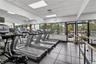 Fitness center featuring large-format tile flooring, floor-to-ceiling mirrored walls, and expansive windows