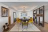 Tray ceiling with recessed lighting, custom floor-to-ceiling metal and glass open-frame partition, multi-arm chandelier, and wide-plank wood-finish fl