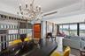 Open-concept interior featuring a multi-arm modern chandelier, custom decorative metal partition wall, wood-paneled feature wall, floor-to-ceiling gla