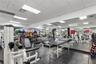 Fitness facility featuring wall-to-wall mirrors, durable rubberized tile flooring, and drop ceiling with recessed lighting