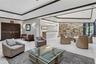 Reception area featuring an expansive tray ceiling, stone-accented wall, recessed lighting, tile flooring, and custom built-in service desk