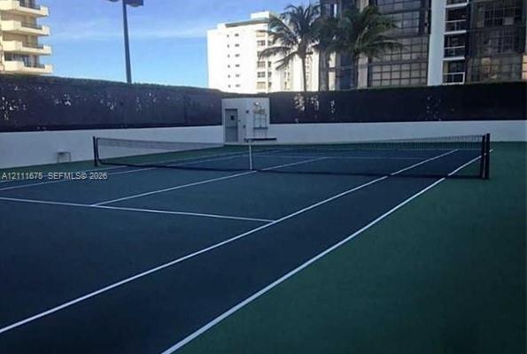 Tennis court featuring a multi-colored hard surface, perimeter wall enclosure, and integrated net