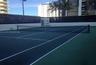 Tennis court featuring a multi-colored hard surface, perimeter wall enclosure, and integrated net