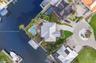 Waterfront property featuring a private swimming pool, concrete boat dock, and a paved circular driveway