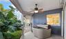 Covered patio featuring a ceiling-mounted light and fan fixture, portable spa, masonry wall finish, and paver walkway