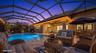 Screened pool enclosure featuring a stone-paver deck and recessed lighting